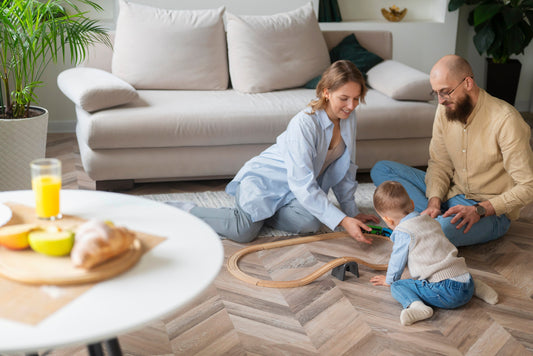 A happy family playing on their living room floor, showcasing beautiful hardwood installed by flooring contractors in Colorado Springs.