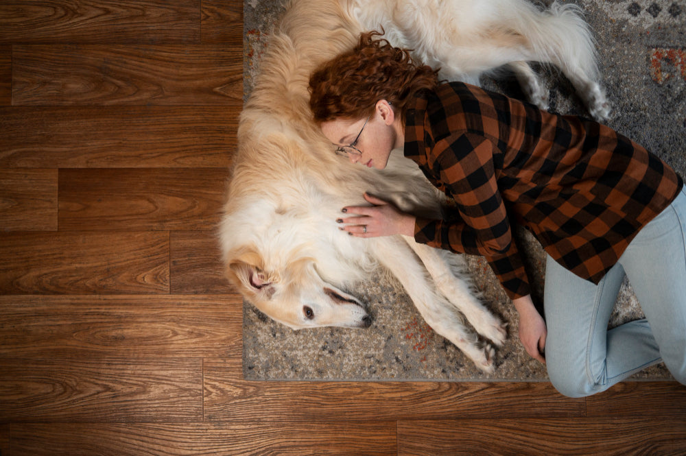 A woman resting beside her dog on hardwood flooring, highlighting a cozy and pet friendly home interior space.