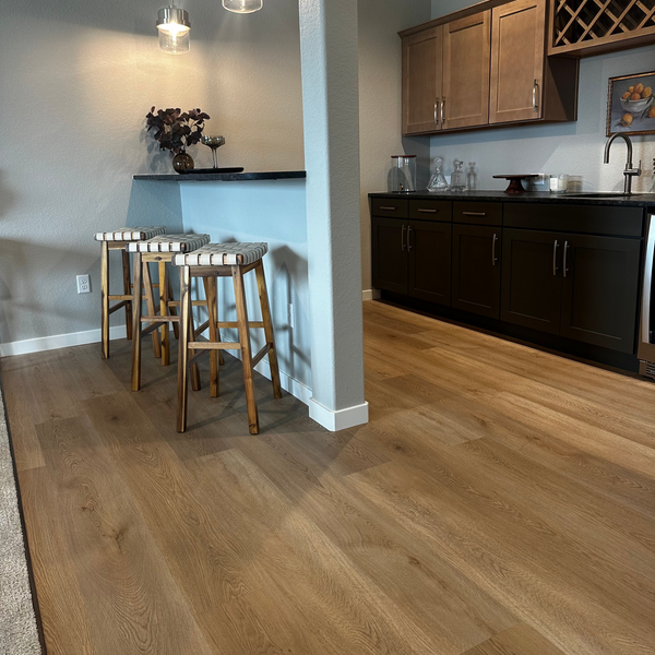 Kitchen with wooden floor, bar stools, and cabinets.