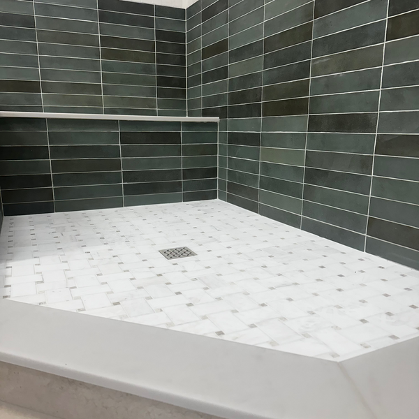 Tiled shower with a white bench and drain